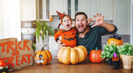 happy Halloween! family father and child daughter getting ready for holiday cutting a pumpkinの写真素材