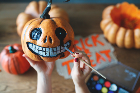 a woman artist prepares for halloween and paints pumpkinsの写真素材