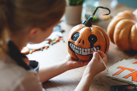 a woman artist prepares for halloween and paints pumpkinsの写真素材