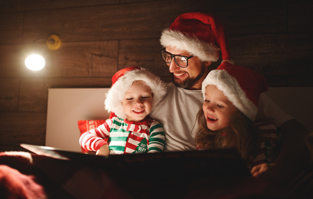 Merry Christmas! family father reads to children a book before bed in bedの写真素材