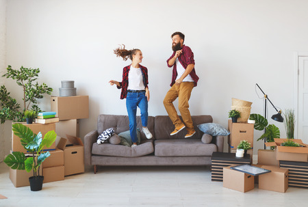 a happy young married couple moves to new apartment and laughing,  jump, fight pillowsの写真素材