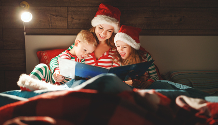 Merry Christmas! family mother reads to children a book before bed in bedの写真素材