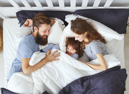 happy family mother, father and  father child daughter in bedの写真素材