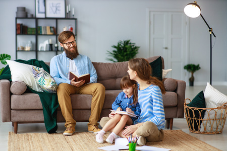 happy family mother father and child daughter draw and read at home on the couchの写真素材