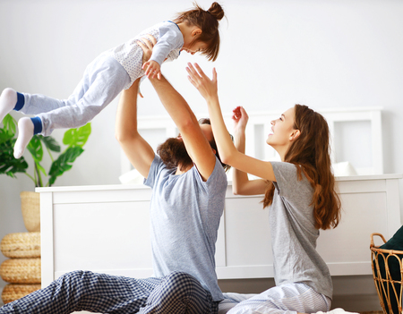 happy family mother, father and  father child daughter in bedの写真素材