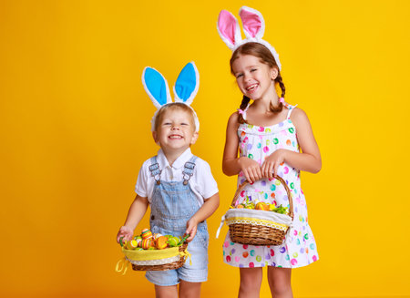 funny happy child boy with easter eggs and bunny ears on yellow background