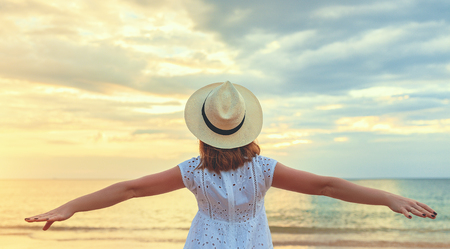 happy woman opened her hands on the beach at sea at sunsetの写真素材