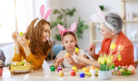 Happy Easter! Family grandmother, mother and child paint eggs and prepare for the holidayの写真素材