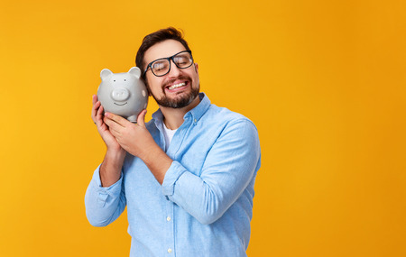 Concept of finance and business. A man with piggy bank on a yellow backgroundの写真素材