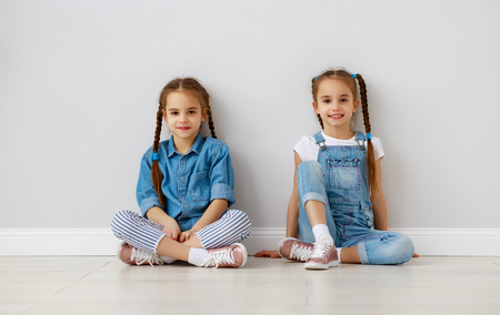 Happy fun kids girls twins at the empty white wall backgroundの写真素材