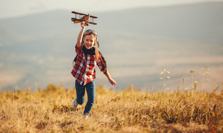 Child pilot aviator with airplane dreams of traveling in summer in nature at sunset