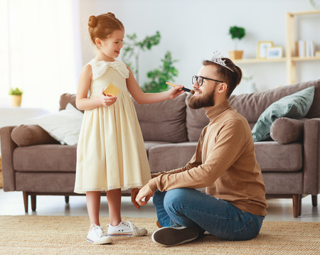 Happy father's day! child daughter in crown does makeup to daddy and laughsの写真素材