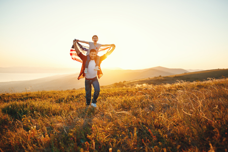 happy family father and child with flag of united states enjoying sunset on natureの写真素材