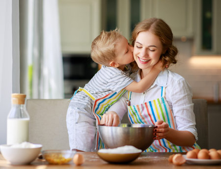 Happy family mother and child son bake kneading dough in the kitchen