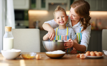 Happy family mother and child son bake kneading dough in the kitchenの写真素材