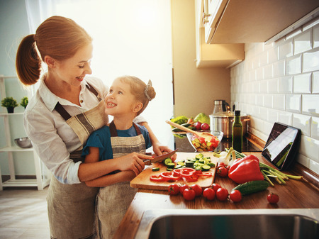 happy family mother with child girl   preparing vegetable salad at homeの写真素材