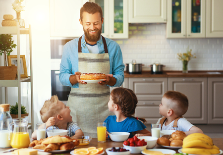 happy family father with many children feeds his sons and daughter in kitchen with Breakfastの写真素材
