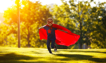 concept happy child superhero hero in red cloak at sunset in natureの写真素材