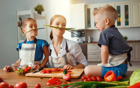 mother with children preparing vegetable salad at homeの写真素材