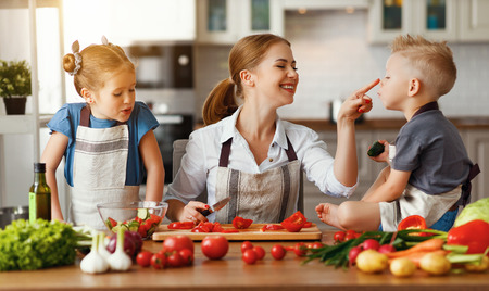 mother with children preparing vegetable salad at homeの写真素材