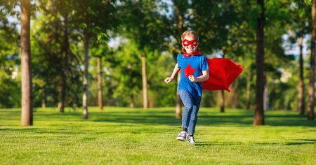 concept happy child superhero hero in red cloak at sunset in natureの写真素材