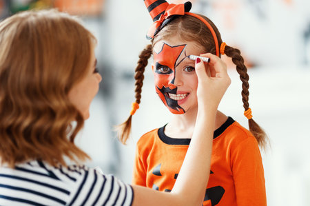 happy family mother and child daughter getting ready for halloween make make-up