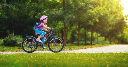 Happy cheerful child girl riding a bike in Park in the natureの写真素材