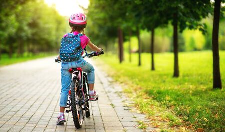 Happy cheerful child girl riding a bike in Park in the natureの写真素材
