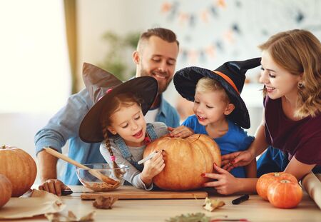 Happy Halloween! family mother father and children cut a pumpkin for holiday at home.の写真素材