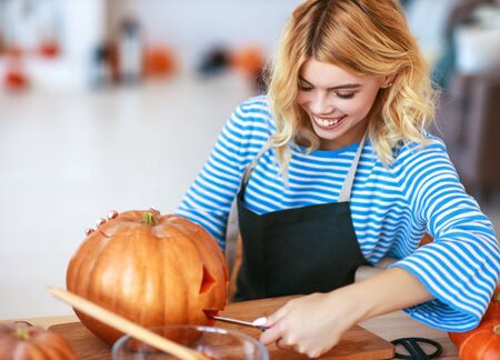 happy girl is cutting a pumpkin and is preparing for the holiday Halloweenの写真素材