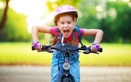 happy cheerful child girl riding a bike in Park in the natureの写真素材