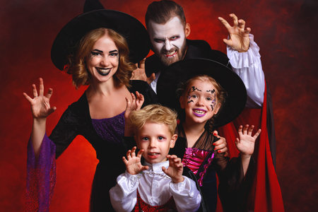 happy family mother father and children in costumes and makeup on a celebration of Halloween on dark...