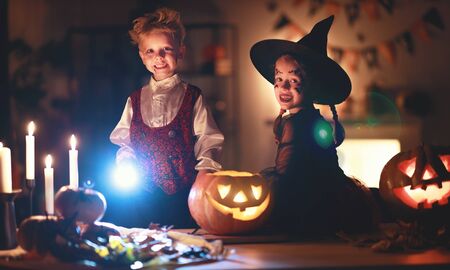 happy children in costumes of witch and vampire  in a dark house in   holiday Halloweenの写真素材