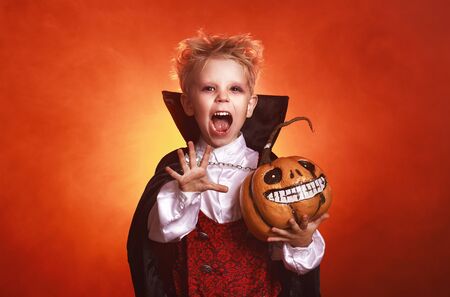 happy child  boy in costumes of vampire in a dark red background in   holiday Halloweenの写真素材