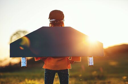 Child pilot aviator with wings of airplane dreams of traveling in summer in nature at sunsetの写真素材
