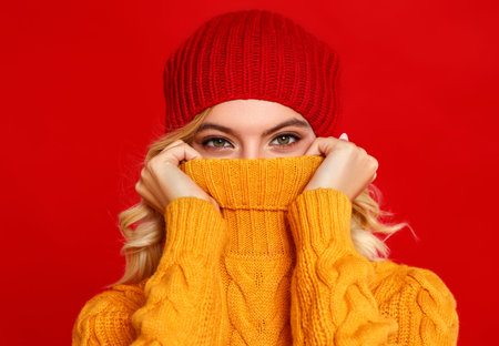 young happy emotional cheerful girl laughing  with knitted autumn cap   on colored red background