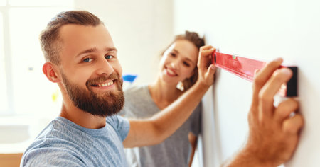 young happy couple is repairing and painting the wall at home