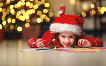 child girl writing letter santa home near the Christmas tree