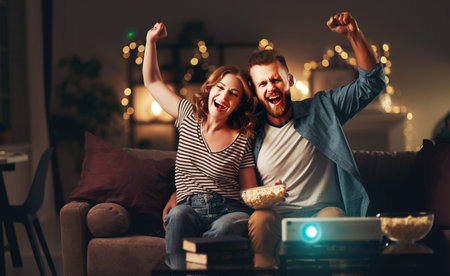 Family couple watching television projector at home on the sofaの写真素材