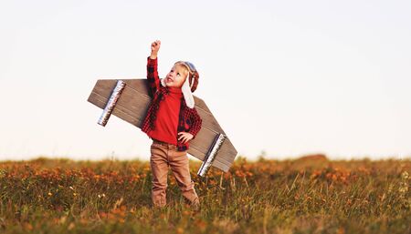 Child pilot aviator with wings of airplane dreams of traveling in summer in nature at sunsetの写真素材