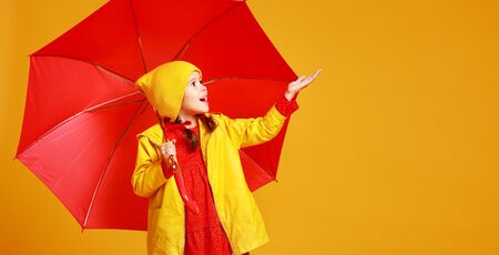 happy emotional cheerful child girl laughing  with red umbrella   on colored yellow backgroundの写真素材