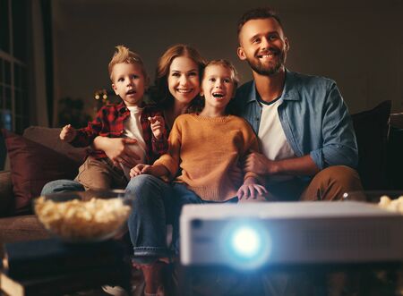 family mother father and children watching projector, TV, movies with popcorn in the evening   at homeの写真素材