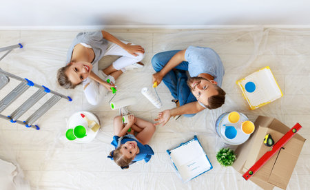 Repair in the apartment. Happy family mother, father  and child daughter    paints the wall with  ...