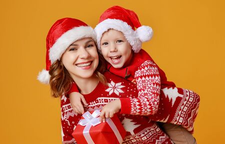 happy family mother and child son with christmas gifts and hats on yellow backgroundの写真素材