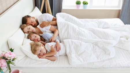 healthy sleep. happy family parents and children sleeping in white bed at homeの写真素材