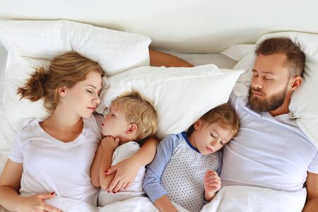 healthy sleep. happy family parents and children sleeping in white bed at homeの写真素材