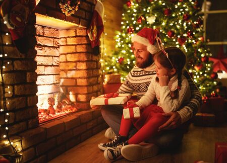 happy family father and child daughter giving christmas gift and embracingの写真素材