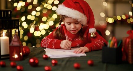 happy child girl writing letter santa home near the Christmas treeの写真素材