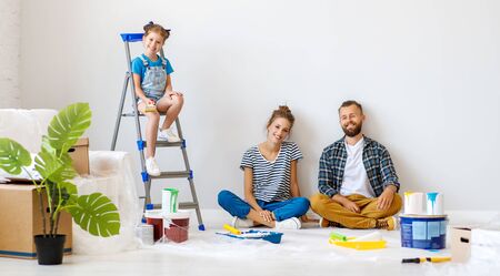 Repair in the apartment. Happy family mother, father  and child daughter    paints the wall with   paint
の写真素材