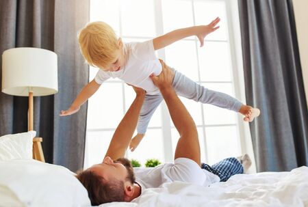 happy family father and child son at home in bed in bedroomの写真素材